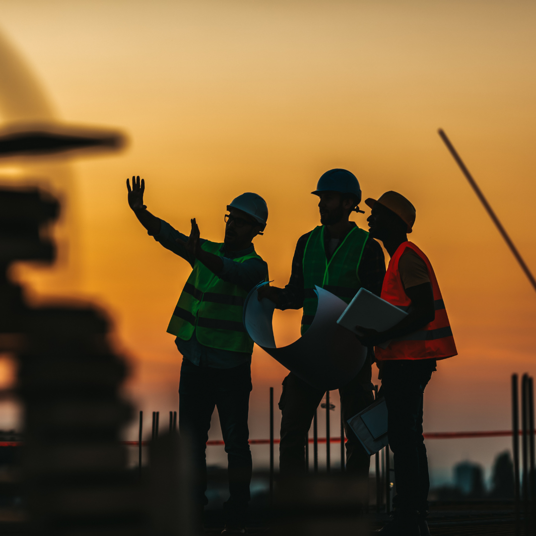 Construction crews wearing high-visibility safety vests at sunset, ensuring roadway and jobsite safety.